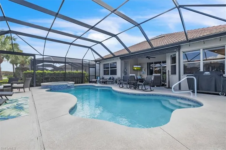Screen-enclosed pool area with a curvilinear pool, integrated spa, and concrete decking