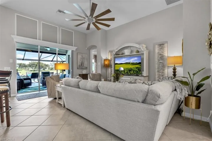 Tiled flooring throughout, high ceilings, large ceiling fan, built-in entertainment center, and sliding glass doors leading to an outdoor screened area