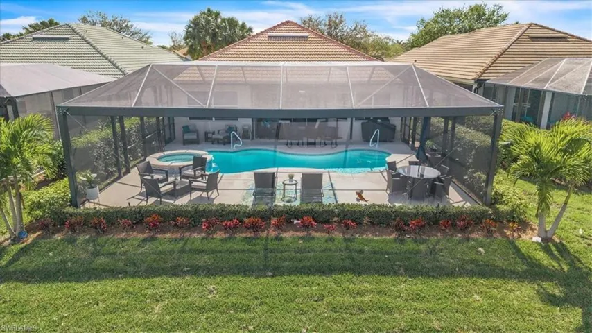 Screened enclosure featuring a swimming pool, integrated spa, and concrete patio