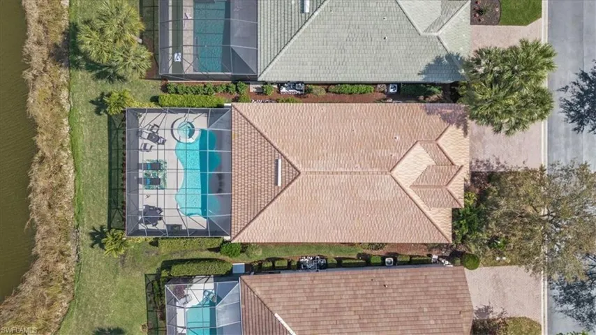 Screened-in pool with integrated spa, tile roof, and manicured landscaping