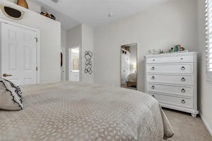Carpeted bedroom with a vaulted ceiling and a paneled door