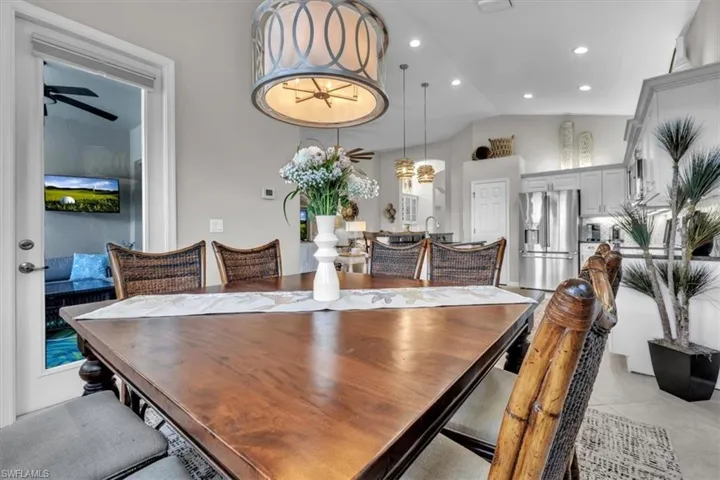 Recessed lighting, vaulted ceiling, built-in cabinetry, stainless steel French door refrigerator, and a glass-paneled door