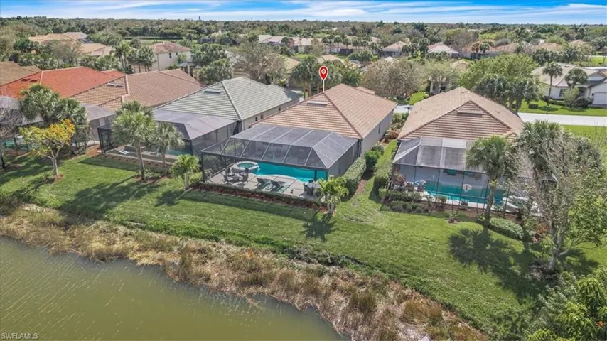 Screened-in pool and spa, expansive patio area, mature palm trees, tiled roof, and lush green lawn