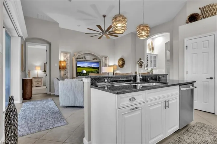 Kitchen island with granite-finish countertop, stainless steel sink, and white cabinetry