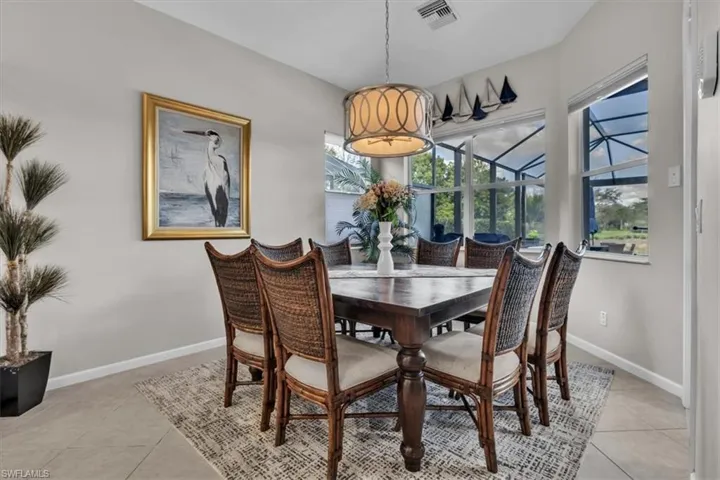 Recessed lighting, tiled flooring, drum pendant light fixture, multiple windows with a pool cage visible beyond