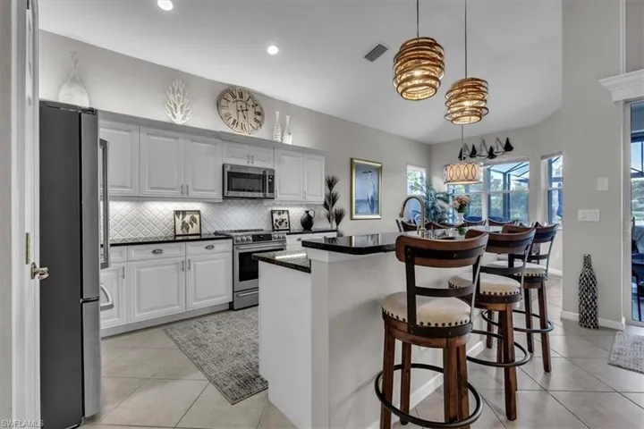 Kitchen featuring white cabinetry, stainless steel appliances, dark countertops, and tile flooring