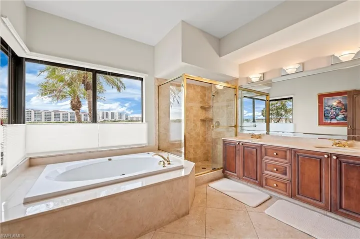 Primary Bathroom featuring vanity, tile patterned flooring, and independent shower and jet tub with water views.