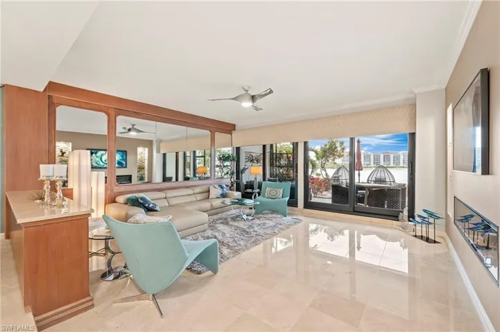 Living room featuring ceiling fan and ornamental molding, custom mirror, electric fireplace with adjustable colored lighting, built-in display shelves, flat-screened television.