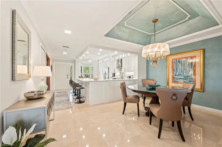 Dining area with tray ceiling, chandelier. View to kitchen and breakfast counter area.