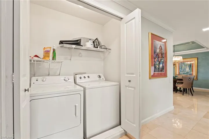Laundry closet featuring washer and clothes dryer and ornamental molding