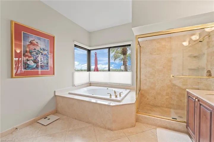 Primary Bathroom with tile patterned floors, vanity, and plus walk in shower and jetted tub.