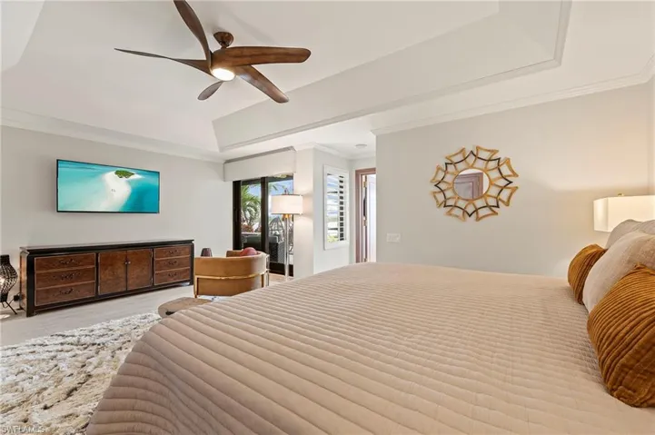 Primary Bedroom with ceiling fan, crown molding, light wood-style tile flooring, and a raised ceiling.