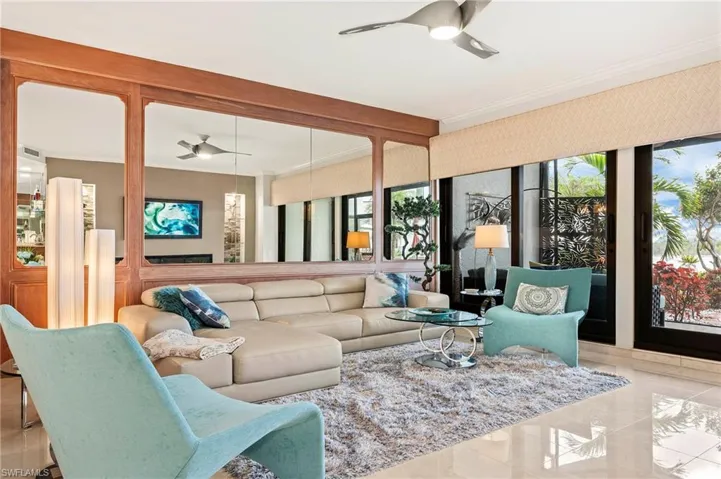 Living room featuring ceiling fan and ornamental molding, lanai access and water views.