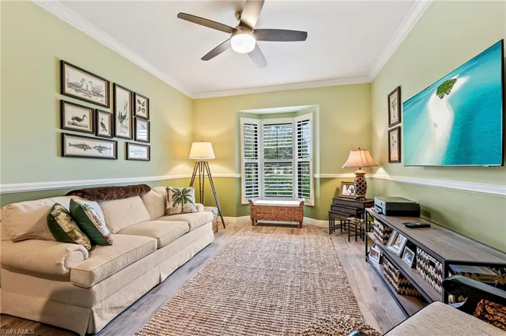 Guest bedroom/sitting room. Featuring ceiling fan, ornamental molding, and wood-style tile flooring, buuilt-in desk area, pull-out queen-sized sofa bed.