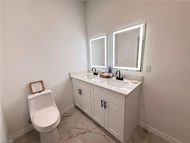 Bathroom with double vanity and marble finish floors