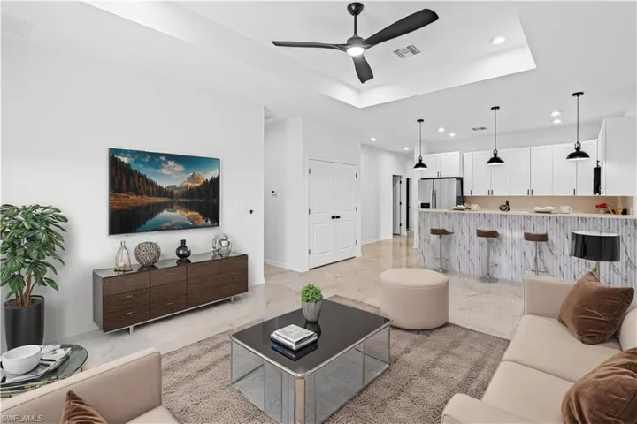 Living room featuring recessed lighting, a ceiling fan, light marble finish floors, and a tray ceiling