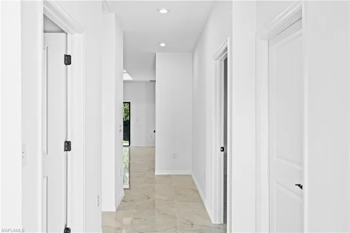 Hallway with light marble finish floors and recessed lighting