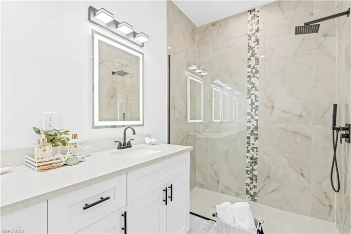 Bathroom with vanity and a marble finish shower
