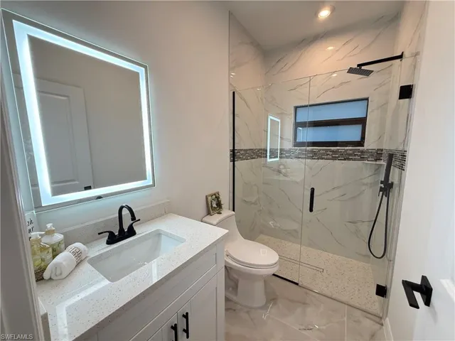 Full bath featuring a marble finish shower, vanity, marble finish flooring, and recessed lighting