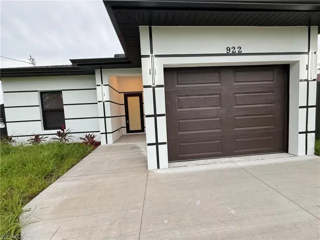 View of exterior entry with concrete driveway and a garage