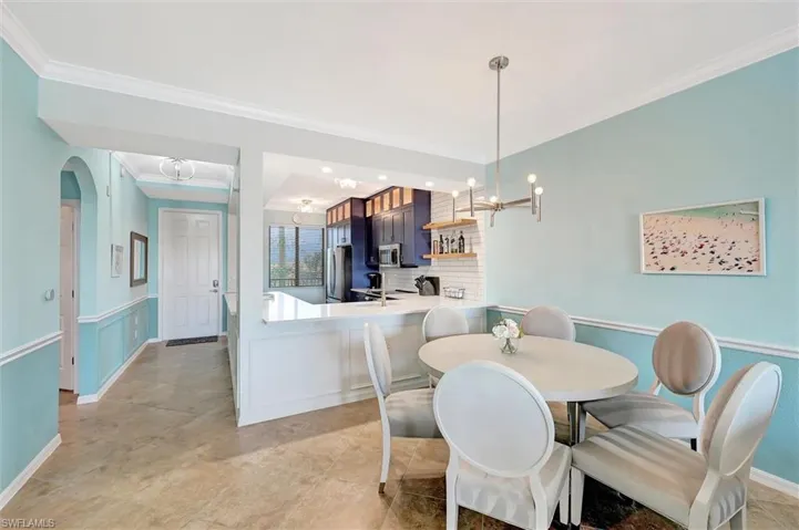 Dining space featuring ornamental molding, a chandelier, and arched walkways