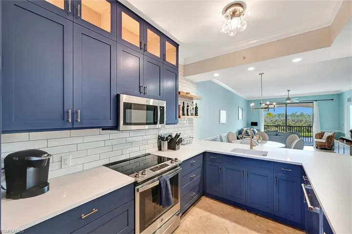 Kitchen featuring blue cabinetry, appliances with stainless steel finishes, crown molding, backsplash, and open floor plan