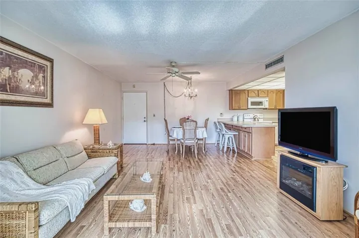 Living area featuring a textured ceiling, light wood-style floors, a chandelier, and a ceiling fan