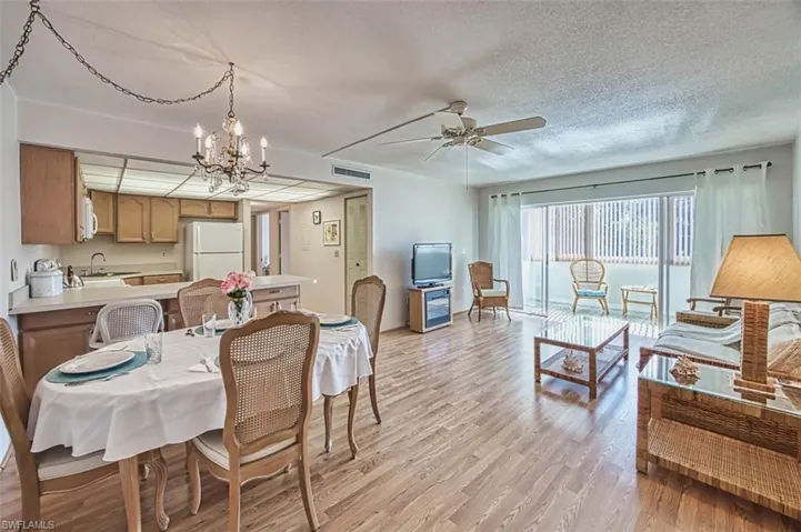 Dining area with a chandelier, light wood-style floors, ceiling fan, and a textured ceiling