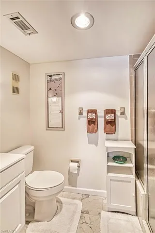 Primary Full bath featuring a shower with shower door, vanity, and marble finish floors