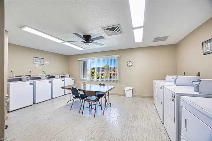 Community laundry room featuring separate washer and dryer, a ceiling fan, light wood-style floors, and a textured ceiling