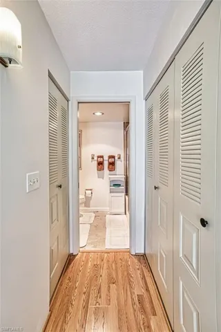 Corridor with light laminate floors and a textured ceiling