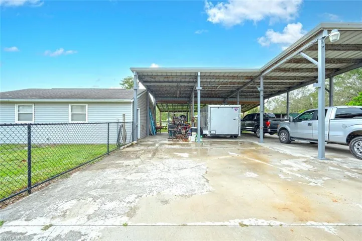 View of parking / parking lot featuring a carport and a yard