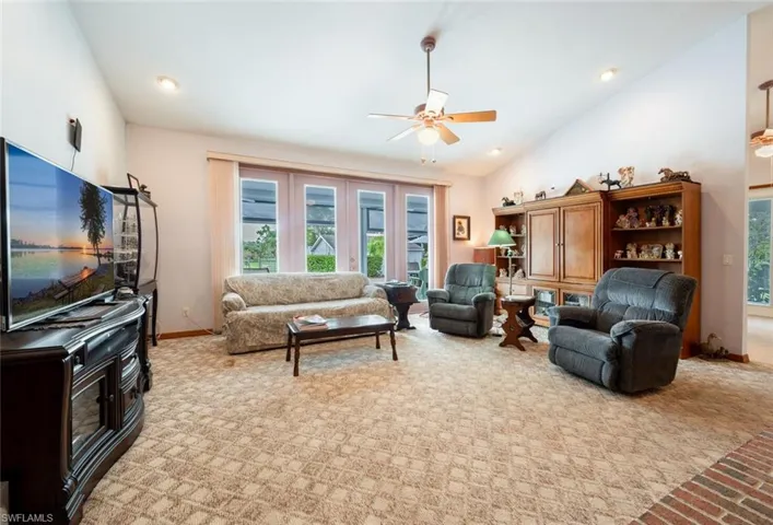 Carpeted living room featuring high vaulted ceiling and ceiling fan
