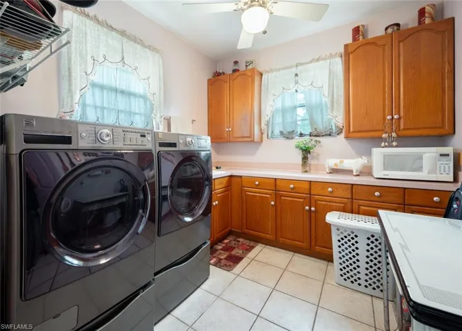 Laundry area with independent washer and dryer, a healthy amount of sunlight, light tile patterned floors, and ceiling fan