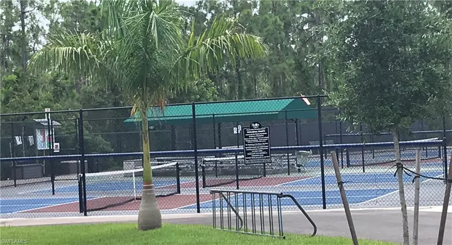 Recreational courts featuring blue and red playing surfaces, enclosed by black chain-link fencing