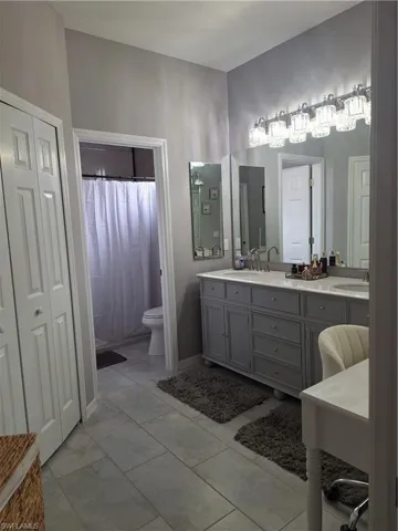 Dual sink vanity with grey cabinetry, white countertop, and prominent overhead lighting fixture