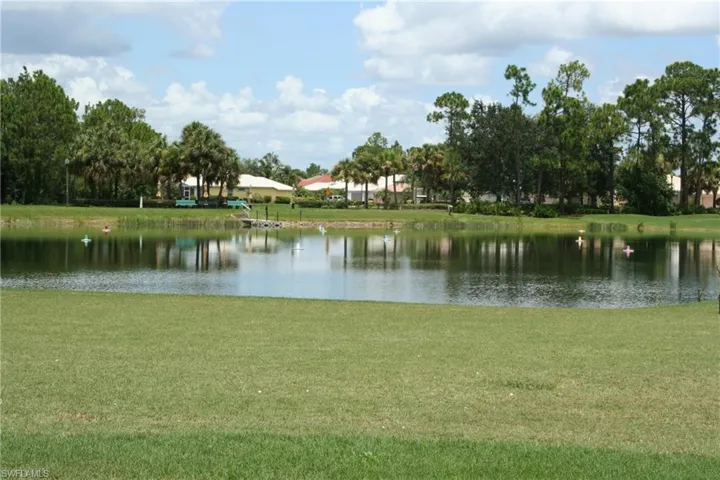 Waterfront property with a lush green lawn, mature palm trees, and a private dock
