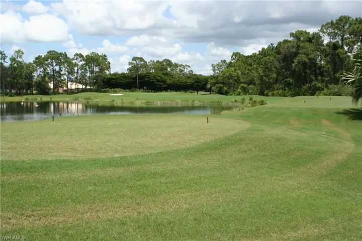 Golf course featuring a water hazard, expansive green, and distant sand trap