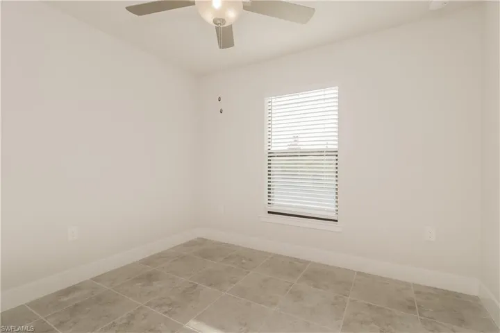 Unfurnished room featuring ceiling fan and light tile floors