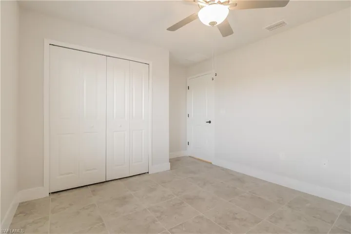 Unfurnished bedroom featuring ceiling fan, a closet, and light tile flooring