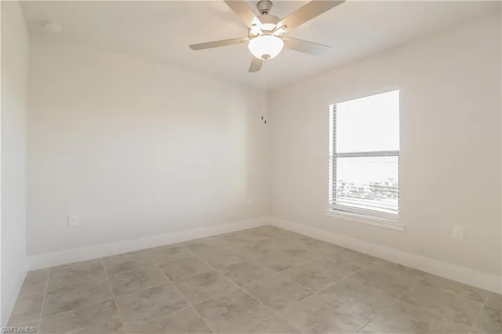 Tiled empty room featuring ceiling fan