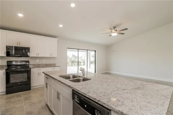 Kitchen featuring black appliances, sink, white cabinets, and ceiling fan