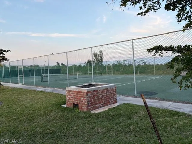 View of tennis court with a yard