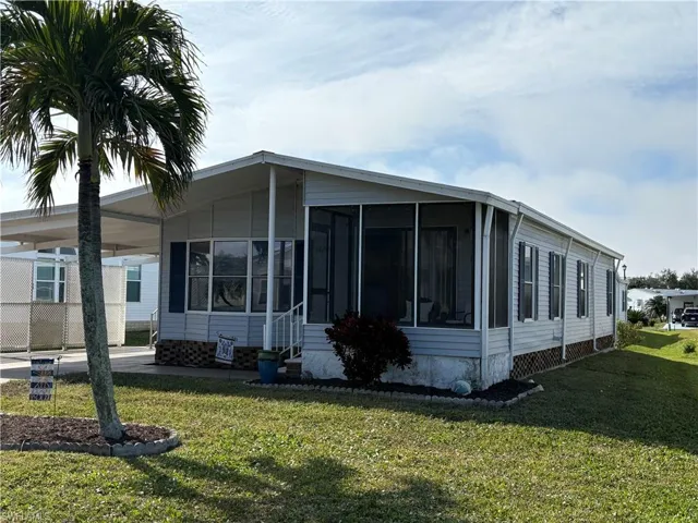 View of home's exterior with a carport, a sunroom, and a yard