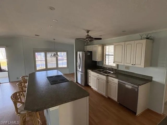 Kitchen with dark countertops, a kitchen breakfast bar, a sink, and stainless steel appliances