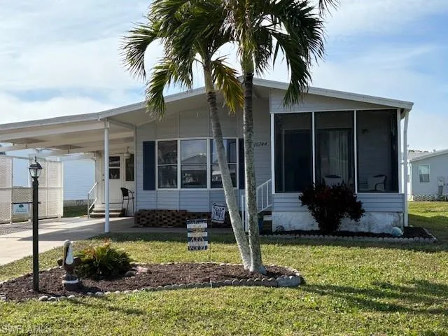 Manufactured / mobile home with a carport, a sunroom, and a front yard