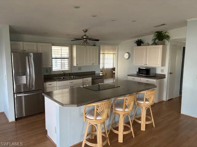 Kitchen with stainless steel appliances, dark countertops, a ceiling fan, dark wood finished floors, and a sink