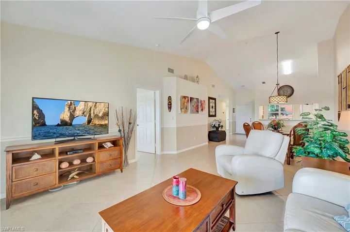 Living room with high vaulted ceiling, ceiling fan, and light tile patterned flooring