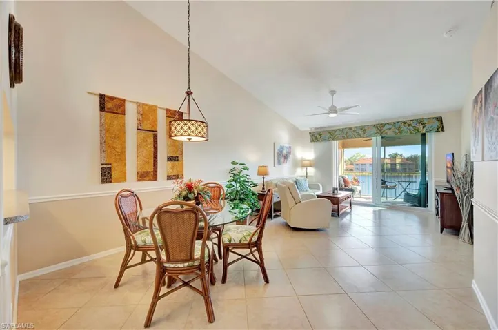 Dining space featuring ceiling fan, light tile patterned floors, and lofted ceiling
