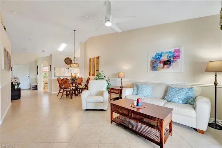 Living room with ceiling fan, light tile patterned floors, and lofted ceiling